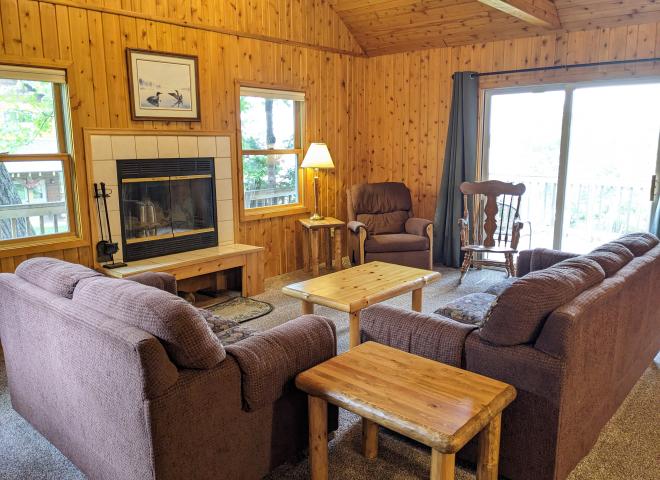 Living room with couch, loveseat, recliner, wood burning fireplace and patio door to the deck.