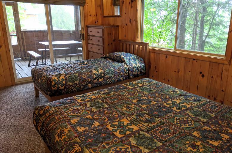 Main floor bedroom with queen, twin, and patio door to the screen porch.