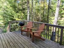 Deck area with chairs and charcoal grill.