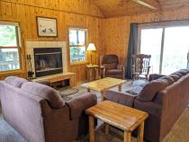Living room with couch, loveseat, recliner, wood burning fireplace and patio door to the deck.